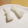 Detail of pearlescent acetate bow hair clips with shimmering finish in a white tray - White