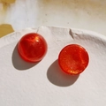 Detailed macro view of 18mm round red acrylic dome cabochon with golden glitter texture - 1 Piece / Orange Red