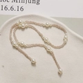 Detailed view of elegant pearl and champagne bead chain displayed on a textured plate - Champagne Gold