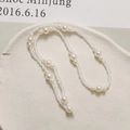 Close-up of elegant long pearl chain with alternating white and clear beads on stone tray - White
