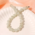 Macro detail of 13mm light green glass beads with gold patterns on a white shell plate - 1 Piece / Light Color