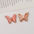 Macro detail of butterfly charm with orange-pink enamel and small zircon stones - Holographic Pink
