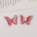Detail of pink butterfly pendant showing rhinestone body and gold metal backing - Iridescent Red