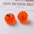 Detailed macro view of orange resin pumpkin pendants with gold loops for DIY jewelry making - One Orange Pumpkin