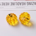 Macro detail of amber resin pumpkin charms with green stems for DIY jewelry making - One Yellow Pumpkin