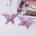 Macro detail of handmade purple beaded butterfly earrings with white pearls and gold accents - Purple