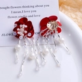Détail de boucles d'oreilles fleurs rouges avec glands en perles sur assiette blanche - Style Gauche Rouge