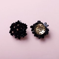 Détail de boucles d'oreilles fleur artisanales avec paillettes noires et base dorée - Noir