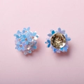 Macro view of iridescent blue woven flower charm with a golden metallic base back - Iridescent Blue