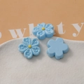 Macro shot of blue resin five-petal cherry blossom DIY charms with yellow centers - Blue