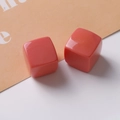 Macro shot of two 20mm glossy coral resin cube charms for DIY jewelry and earrings - Orange