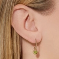 Gold-plated heart-shaped earrings with green zircon pendants shown on model - Drop Earrings