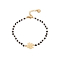 Detailed macro view of black faceted beads and gold four-leaf clover pendant bracelet - Four-Leaf Clover / Gold