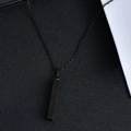 Macro shot of minimalist matte black rectangular bar pendant with slim cross chain necklace - 4x30mm / Black