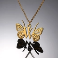 Detailopname van de gouden vlinderketting met letter W op een donker reflecterend vlak - Letter W