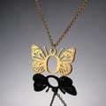 Macro-opname van gouden vlinderhanger met opengewerkte vleugels aan fijne O-ketting - Letter O