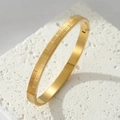 Polished gold stainless steel bangle featuring Greek key pattern and secure clasp closure - Gold