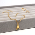 Minimalistische goldene Halskette mit Buchstaben A Anhänger auf grauem Samt-Schmucktablett - Buchstabe A Stil (Gold A)