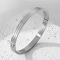 Detailed close-up of silver steel bangle featuring Greek Key engraving and side hinge - Steel