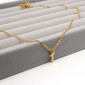 Minimalistische vergoldete Edelstahl-Kreuzkette auf einem grauen Samt-Schmucktablett - Buchstabe T Stil (Gold T)