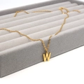 Elegante vergoldete Edelstahlkette mit dem Großbuchstaben W auf grauem Schmucktablett - Buchstabe W Stil (Gold W)