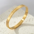 Titanium steel gold oval bangle featuring continuous Greek meander pattern and side clasp - Gold