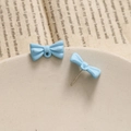 Macro detail of blue bow-knot stud earrings with matte finish on textured background - Blue