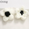 Macro shot of handmade crochet puff flowers in black and white on a ceramic tray - Black