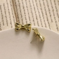 Detailed view of gold ribbon bow earrings and charms on a vintage aesthetic background - Gold