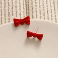 Detail view of red bow earrings with matte finish showing front and stud back structure - Red