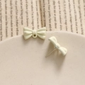 Macro shot of matte cream bow earring studs and jewelry pendant components with metal pins - White