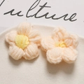 Close-up of pink and yellow handmade crochet puff flower accessories on a ceramic plate - Pink and Yellow Heart