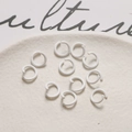 Close-up of white macaron color metal jump rings for DIY jewelry making on beige tray - White