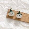 Macro detail of pumpkin wizard pendants with shiny green hats and metal rings - White
