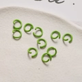Dettaglio di nove anellini aperti 8mm verde brillante su vassoio per creazione gioielli - Verde