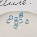 Dettaglio di anellini aperti da 8mm in lacca blu cielo su un vassoio di ceramica - Azzurro