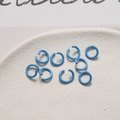 Macro di anellini aperti in metallo laccato blu brillante su vassoio in ceramica - Blu Zaffiro