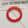 Gros plan d'un ornement circulaire en perles rouges nacrées avec épingle en métal doré - 1 Pièce / Rouge