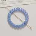 Détail macro d'un charme rond bleu iridescent avec tige dorée pour création de bijoux - 1 Pièce / Bleu
