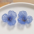 Detailed close-up of handmade blue crystal beaded flower earrings on white ceramic plate - Purple