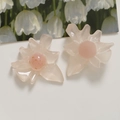 Macro shot of translucent pink flower charms with gold leaf details on white surface - Light Pink