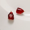 Close-up of translucent red ghost charms with glitter hearts and gold DIY rings - Red + Pink Heart