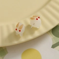 Macro de boucles d'oreilles lapin blanc sur assiette en céramique pour bijoux faits main - Jaune
