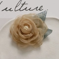 Detailed close-up of champagne organza rose flower with white stamen and blue mesh leaves - Coffee