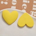 Detailed macro view of yellow matte heart-shaped studs on a minimalist white tray - Yellow