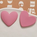 Macro shot of matte pink heart-shaped earrings on a white textured ceramic plate - Deep Pink