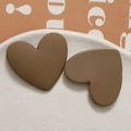 Macro shot of matte chocolate brown resin heart charms on a white ceramic plate - Dark Coffee