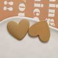 Macro detail of mustard yellow matte resin heart earrings on a ceramic display plate - Light Coffee