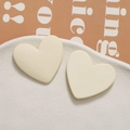 Macro close-up of cream matte heart-shaped resin stud earrings on white ceramic plate - Off White