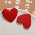 Detail of red matte heart-shaped resin stud earrings on a white textured plate - Red